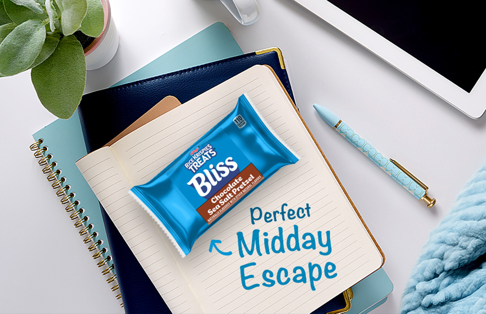 Bliss bar on a desk with a note pad. Perfect midday escape is text bubble next to the bar. 