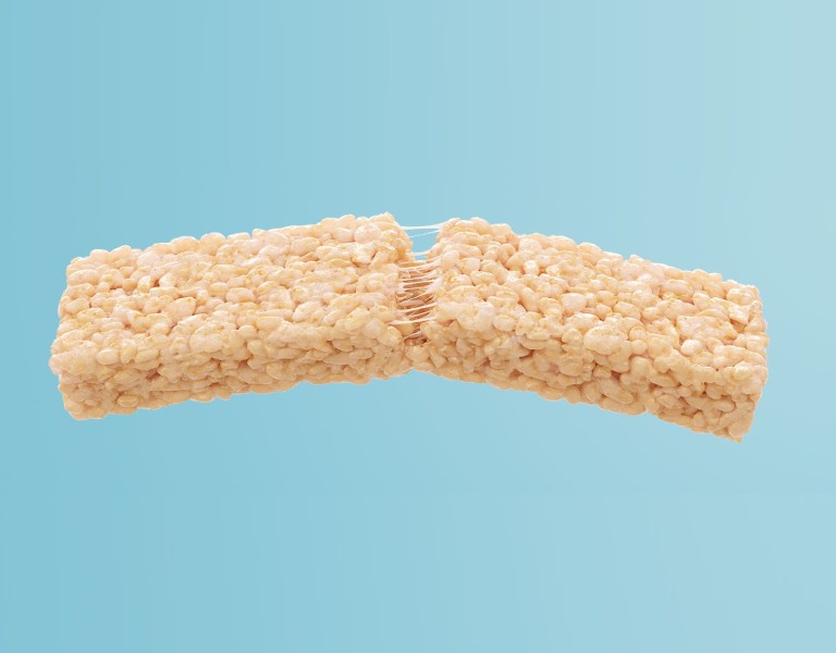 Extra Long Rice Krispies Treats® Floating in a light blue background showing strings of marshmallow in the middle of the treat