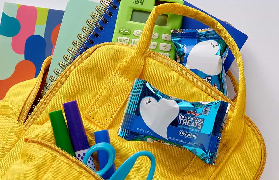 A yellow colored school back pack filled with supplies and two Rice Krispies Treats®
